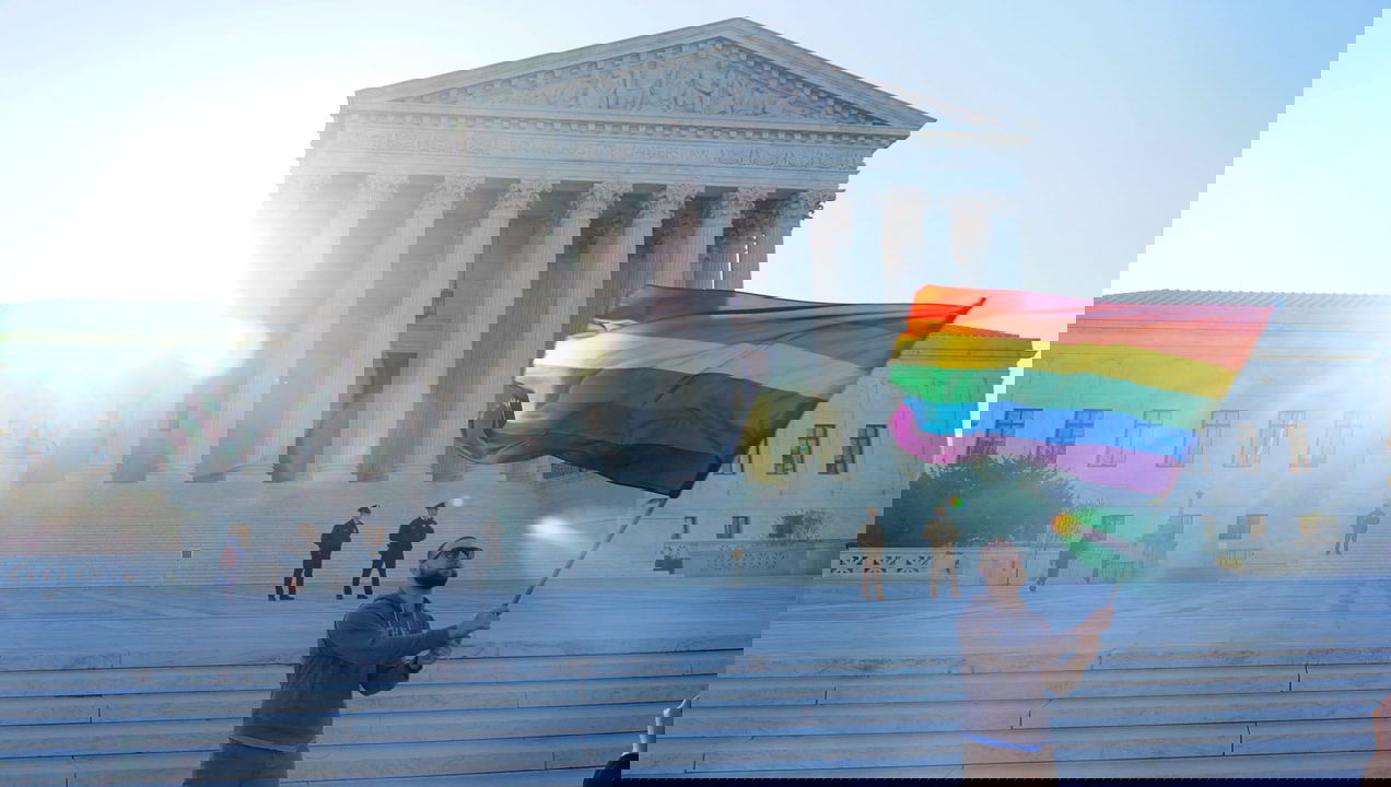 LGBTQ+ flag being waved in front of the U.S. Supreme Court.